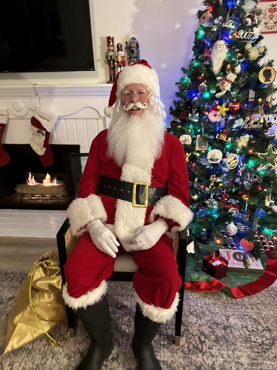 Santa Claus ready for photos with a gold gift sack and fireplace